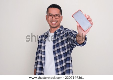 Adult Asian smiling happy while showing blank mobile phone screen