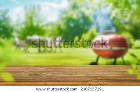 summer time in backyard garden with grill BBQ, wooden table, blurred background Royalty-Free Stock Photo #2307157291