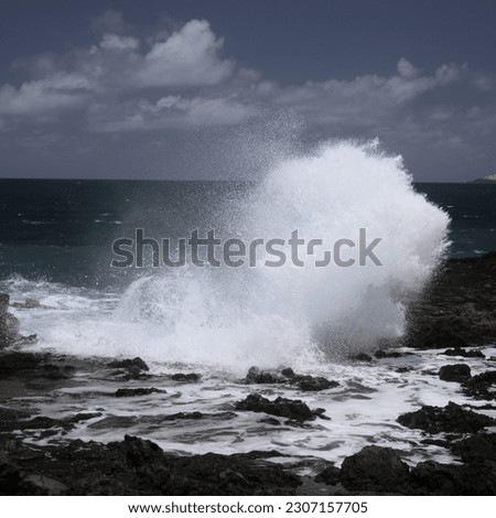 Gran Canaria, north west coast around natural swimming pools Salinas de Agaete, 
waves breaking against old eroded dark lava platform Royalty-Free Stock Photo #2307157705
