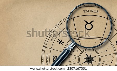 The imprint of the zodiac sign on Taurus old paper is enlarged with a lens Royalty-Free Stock Photo #2307167051