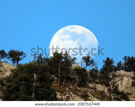 A full moon over the rocky alpine peak of Musflue in the Swiss mountain range of Pilatus and in the Emmental Alps, Alpnach - Canton of Obwalden, Switzerland (Kanton Obwald, Schweiz)