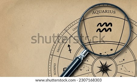 The imprint of the zodiac sign Aquarius on old paper is enlarged with a lens Royalty-Free Stock Photo #2307168303