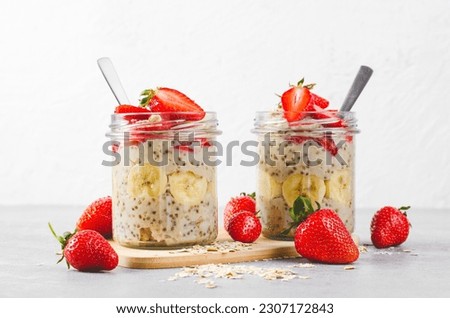 Overnight Oats, Chia Pudding with Fresh Strawberry, Banana and Chia Seeds in Jars on Grey Background, Healthy Snack or Breakfast Royalty-Free Stock Photo #2307172843