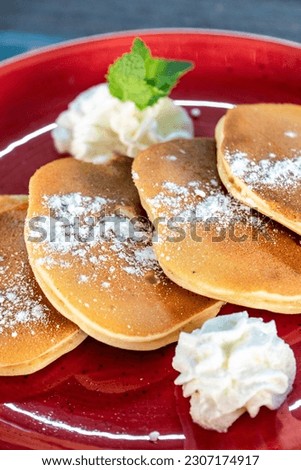 a close up portrait image of sugar covered American style pancakes served with whipped cream 