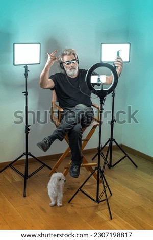 Radio host, charming influencer, records a live show with camera stuff and equipment. Black and white dogs. Colorful studio.