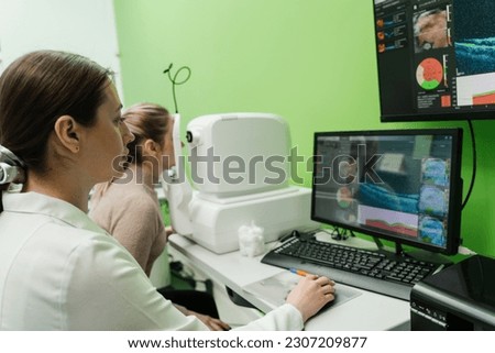 Examination of eyes of patient using optical coherence tomograph. Optical coherence tomography OCT scan to create pictures of the back of eye. Ophthalmologist is scanning cornea of woman patient