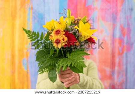 Mature woman hidden by a bouquet of flowers. Celebration concept. Valentine's Day Women's Day birthday holiday party.