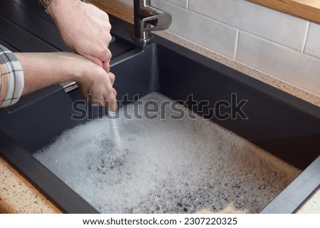 Overflowing kitchen sink, clogged drain, plumbing problems, trying to unclog Royalty-Free Stock Photo #2307220325