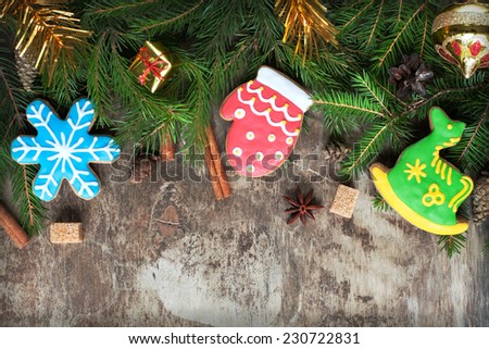 Homemade christmas gingerbreads painted as a green horse, a red mitten and blue snowflake on the wooden background with fir branches. Selective focus and place for text. Toned