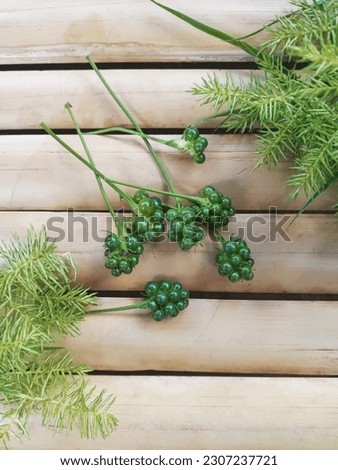 Bunch of Green Lantana Camara Seeds Decorated with Green Grass on Bamboo Background