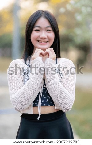 Portrait cute smiles Asian of attractive young teenage girl in Beautiful blooming flowers with outdoor the park in spring day at Evening background