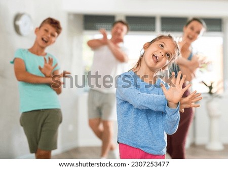 An active, positive family has fun at home. Parents with young daughter and schoolboy son taught to move dance jazz funk
