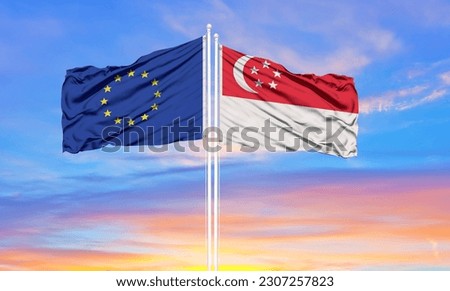 European Union and Singapore two flags on flagpoles and blue cloudy sky . Diplomacy concept, international relations