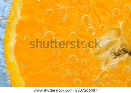 Slice of orange fruit in sparkling water. Orange fruit slice covered by bubbles in carbonated water. Orange fruit slice in water with bubbles. Close-up, macro horizontal image. Detail of orange slice. Royalty-Free Stock Photo #2307266487