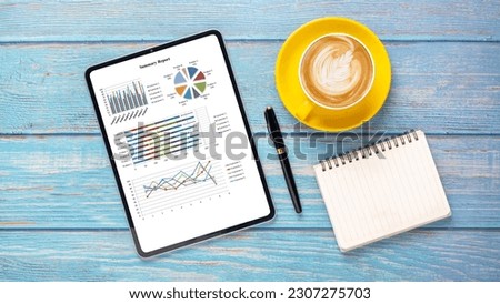 Tablet with charts and reports on office desk workplace. Top view flat lay	

