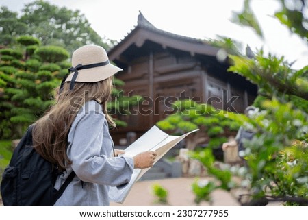 Asian tourist, cute woman with long hair are traveling in Hong Kong along with map and her camera with fun on her holiday, A temple in Hong Kong.