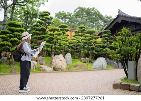 Asian tourist, cute woman with long hair are traveling in Hong Kong along with map and her camera with fun on her holiday, A temple in Hong Kong.