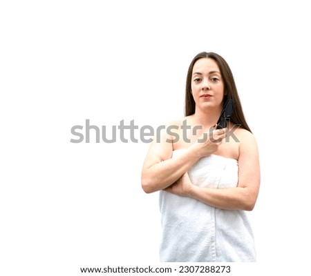 Beautiful young brunette woman posing while wearing a bathroom towel against a white background
