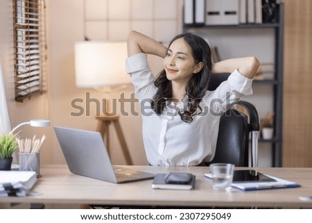 Gorgeous Indian woman stretching in comfy armchair while work indoors. Attractive young lady with laptop, enjoying lazy morning, having peaceful weekend. Stay home hobbies