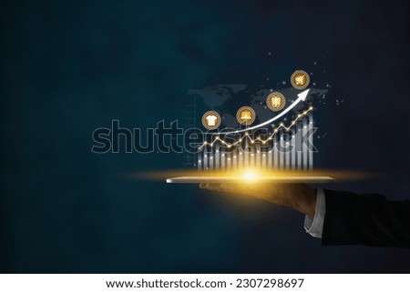 Businessman Hold Tablet and Stock Market Graph,Online Products Icon,Bar Chart,Line Graph. Consumer Discretionary,Consumer Staples,Financial,Economic,Business and Technology Concept in Dark Tone