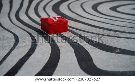 A red gift box that overlaps the curved lines.