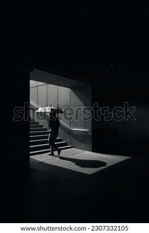 A woman with an umbrella walks through the tunnel, creating a beautiful light and shadow