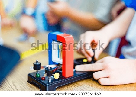 Student with Experimental electric generator, consists of copper coils and magnets. A generator is a device that converts mechanical energy to electrical energy for use in an external circuit.school. Royalty-Free Stock Photo #2307361169
