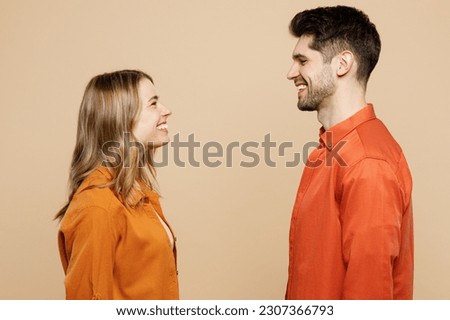 Side view young smiling happy fun cool couple two friends family man woman wearing casual clothes looking to each other together isolated on pastel plain light beige color background studio portrait Royalty-Free Stock Photo #2307366793
