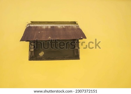 Photo of old glass ventilation window with canopy on yellow walls. With empty blank text copy space.