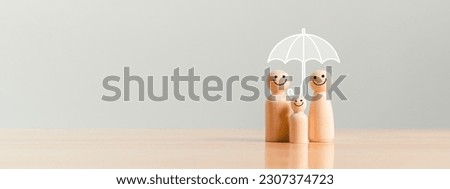 Happy family under the umbrella on raining wooden figurine model on table top background. People lifestyles and Relationships in love concept. Royalty-Free Stock Photo #2307374723