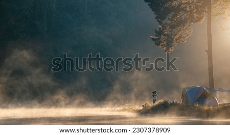 Photographer travel and camping alone at natural park in Thailand. photographer takes pictures morning fog