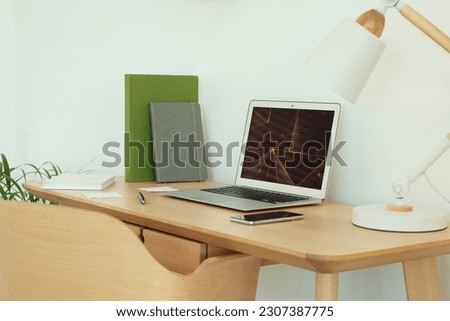 Cozy workspace with modern laptop on desk and comfortable chair at home