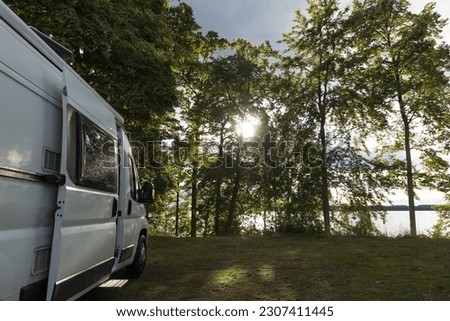 White camper van parking on a beautiful camping pitch at a lake in Sweden.