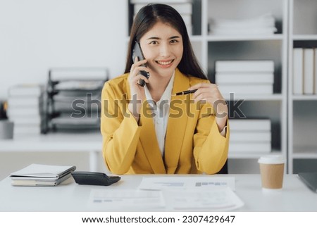 Young female Asian businesswoman having a phone call with her coworker in the office room.