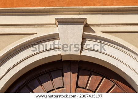 Closeup of an ancient marble arch with keystone and brown wooden door, full frame, photography. Brescia downtown, Lombardy, Italy, Europe.