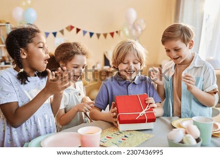 Diverse group of happy children at Birthday party with excited boy opening presents Royalty-Free Stock Photo #2307436995
