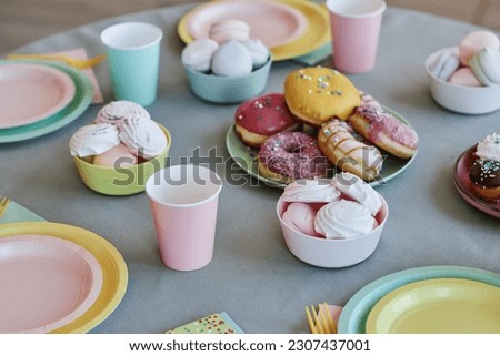 Background image of table with sweets and donuts in pastel colors at kids party, copy space