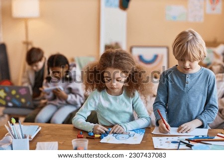 Waist up portrait of two kids drawing together during art class in after school class, copy space
