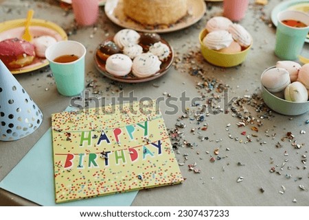 Background image of happy birthday card with glitter and confetti on dinner table with sweets during birthday party for children, copy space