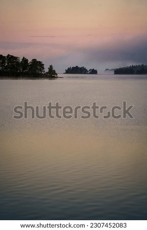 Immeln, Sweden - July 31, 2022: Tranquil Morning Scene Over Immeln Lake with Emerging Islands, Surrounded by a Light Mist, Painting a Breathtaking Picture of Nordic Serenity