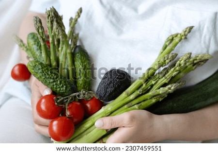 woman girl lying on bed holding in arms vegetables like asparagus,tomatoes,cucumbers,avocado and zucchini.lose weight concept,fat on belly abdoment,healthy nutrition,fibers Royalty-Free Stock Photo #2307459551