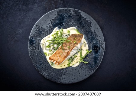 Modern style traditional fried skrei cod fish filet with mashed potatoes and glasswort served as top view on ceramic design plate with copy space 