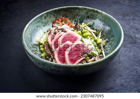 Modern style traditional Japanese gourmet seared tuna fish steak tataki with soba noodles and stir-fried vegetables served as close-up on a Nordic design bowl with copy space Royalty-Free Stock Photo #2307487095