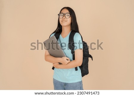 The happy Asian female student wears glasses and has a tablet in her hand