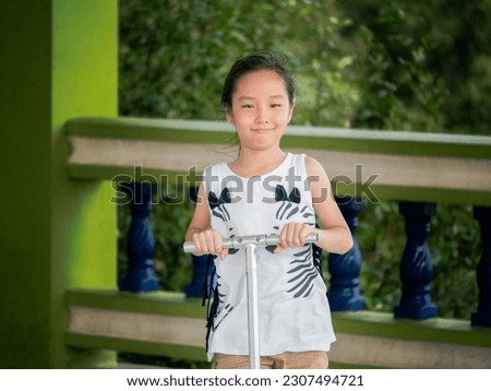 Little asian child girl pilay scooter for children in the park