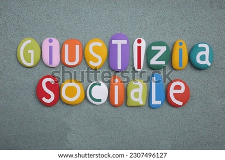 Giustizia Sociale, Social Justice in italian language composed with multi colored stone letters over green sand