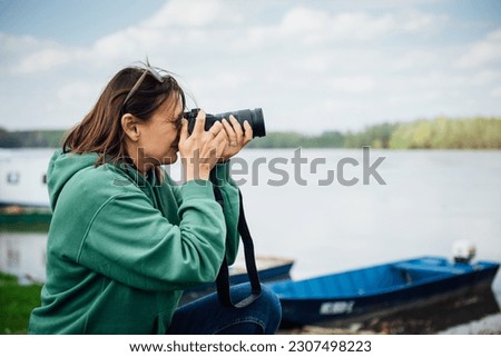 A young female traveler takes pictures with a SLR camera of the views of nature around.