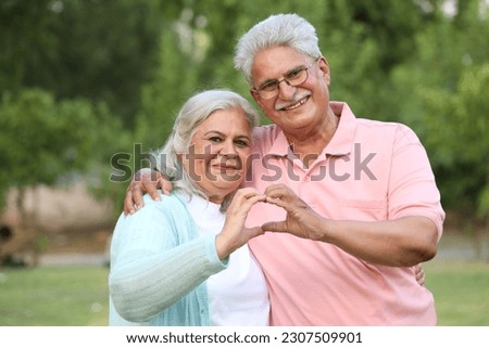 Indian happy senior couple making and showing heart with hands in garden  Royalty-Free Stock Photo #2307509901