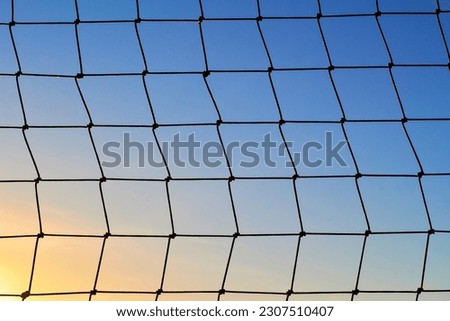 Net to catch balls around a football field, on clear blue sunset sky background