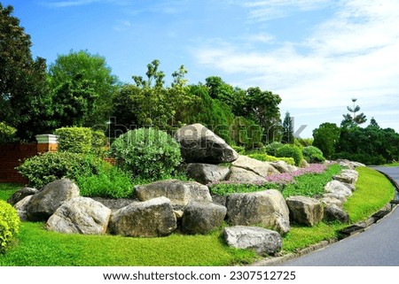 The stone wall garden is planted with ornamental shrubs and flowering plants in the crevices of the rocks.                            Royalty-Free Stock Photo #2307512725